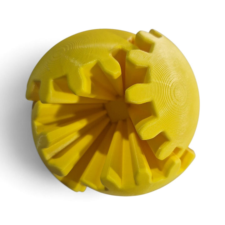 Gear Ball Sense fechada: bola amarela de gomos dentados com as engrenagens pretas à mostra