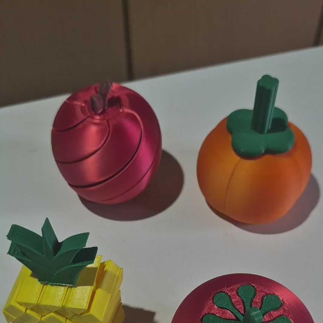 As quatro peças do Kit Feira Sense na mão: abacaxi dobrando, tomate desenroscando, maçã abrindo em espiral e cenoura esticando