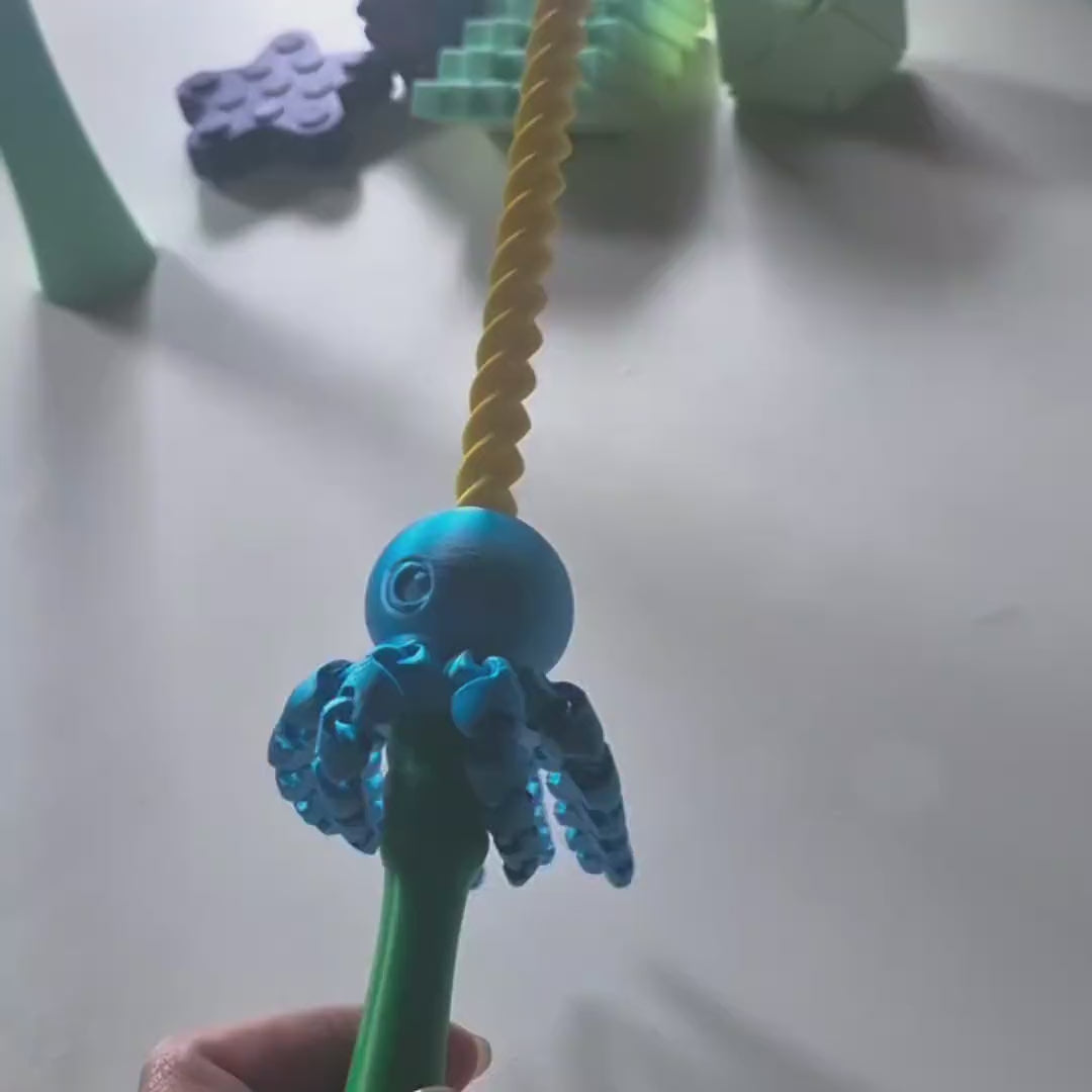 Varinha Mágica balançando na mão: o polvo desliza pela haste em espiral e os tentáculos balançam
