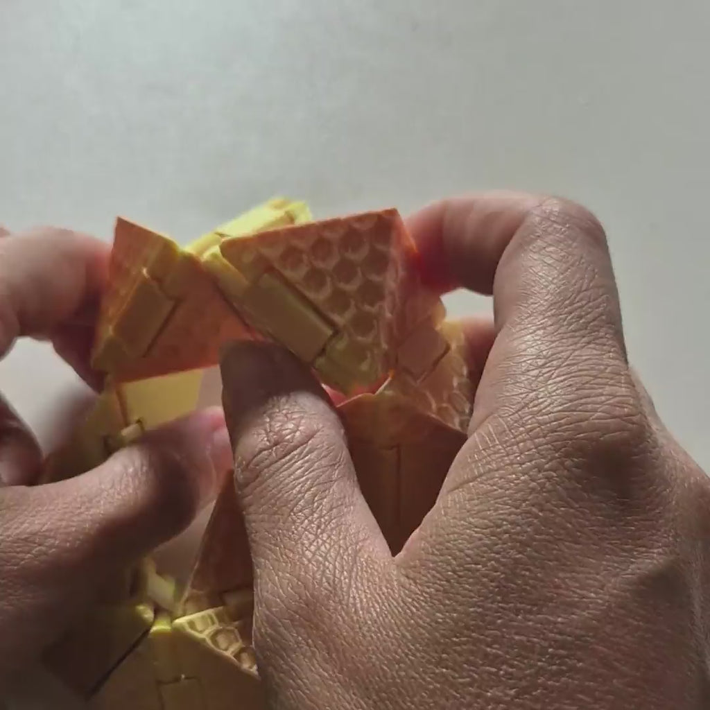 Cubo Origami Sense sendo dobrado nas mãos: sai do anel, passa pela pirâmide e fecha em cubo