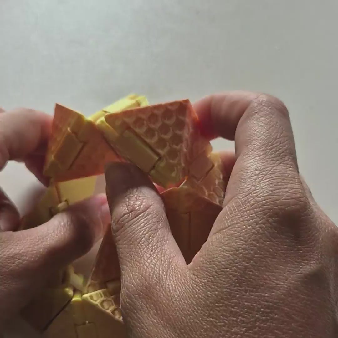 Cubo Origami Sense sendo dobrado nas mãos: sai do anel, passa pela pirâmide e fecha em cubo