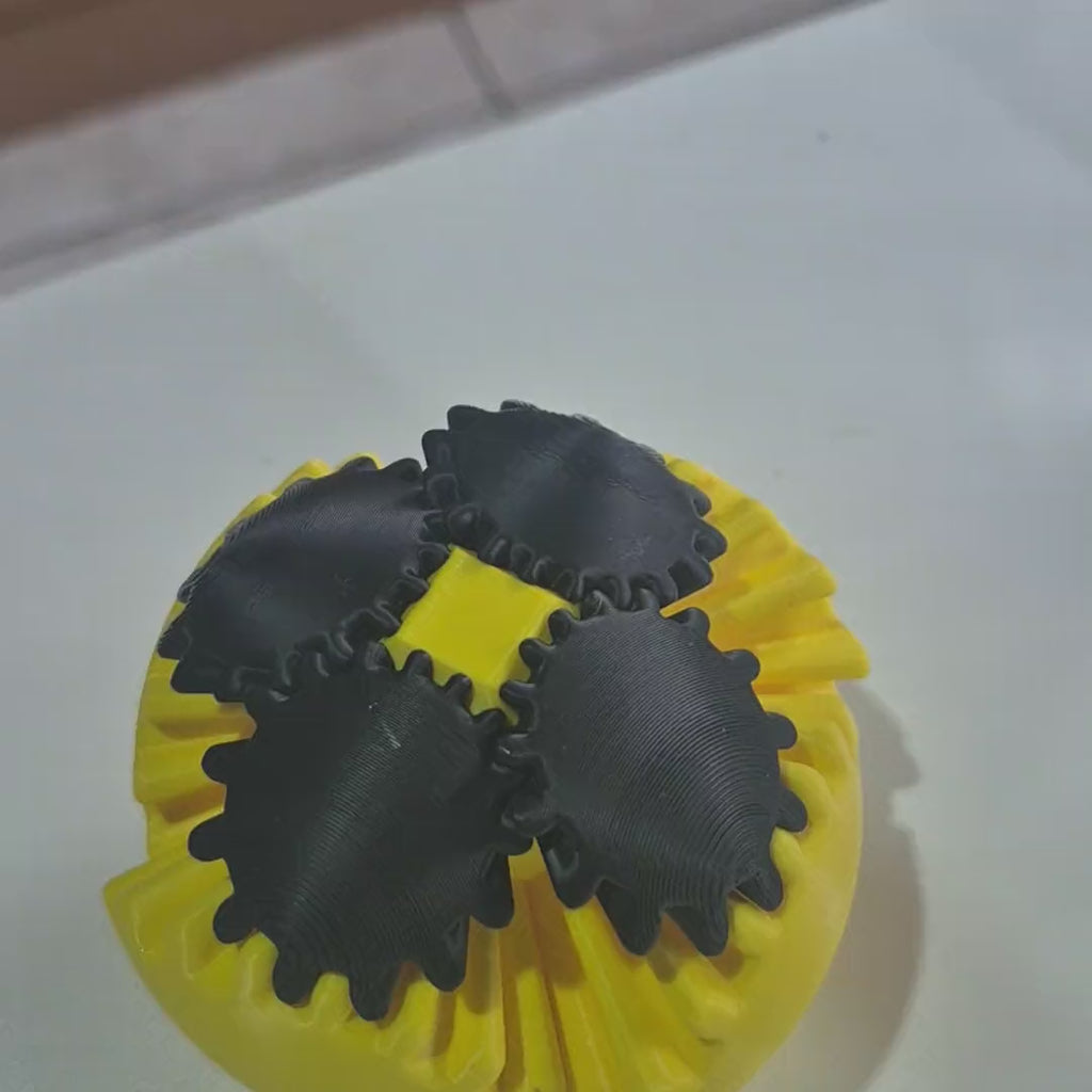 Mão girando as engrenagens da Gear Ball Sense: a bola se abre em pétalas e fecha de novo