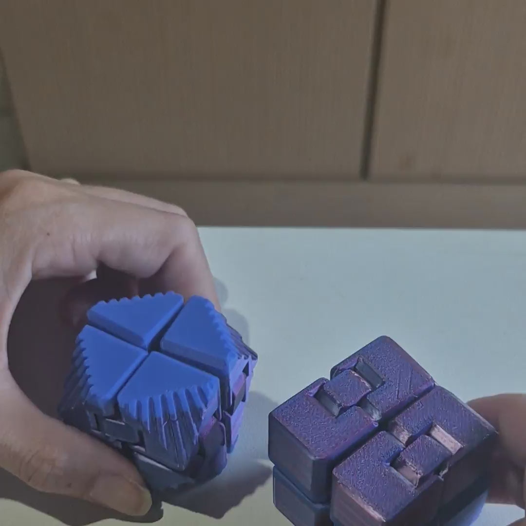 Os dois Cubos Infinitos sendo dobrados na mão — o de faces lisas e o texturizado